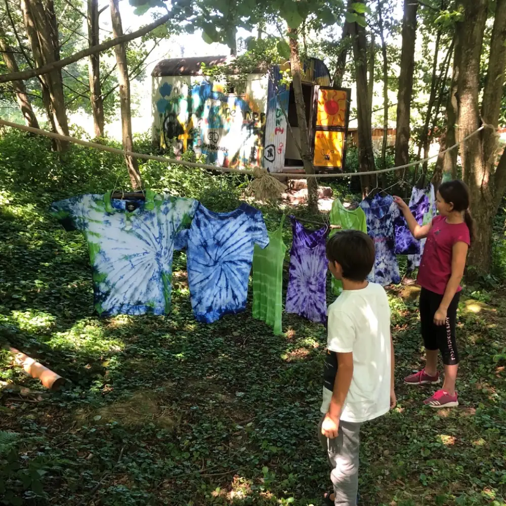 Kinder hängen selbstgefärbte T-Shirts auf.