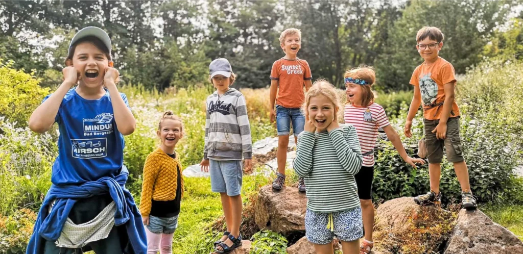 Ein Gruppe von Kinder in der Natur die begeistert schreien.